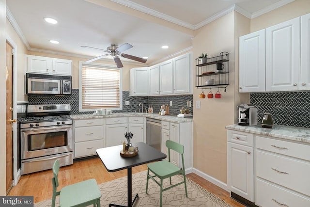 kitchen featuring white cabinets, light wood-type flooring, appliances with stainless steel finishes, and backsplash