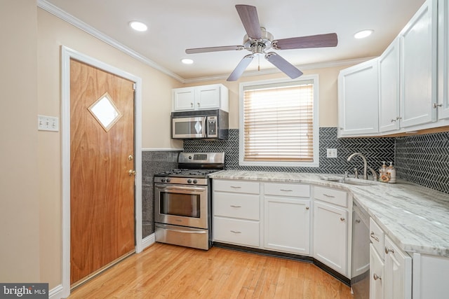 kitchen featuring appliances with stainless steel finishes, light hardwood / wood-style floors, light stone countertops, sink, and white cabinetry