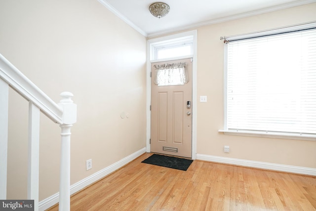 foyer entrance with ornamental molding and light wood-type flooring