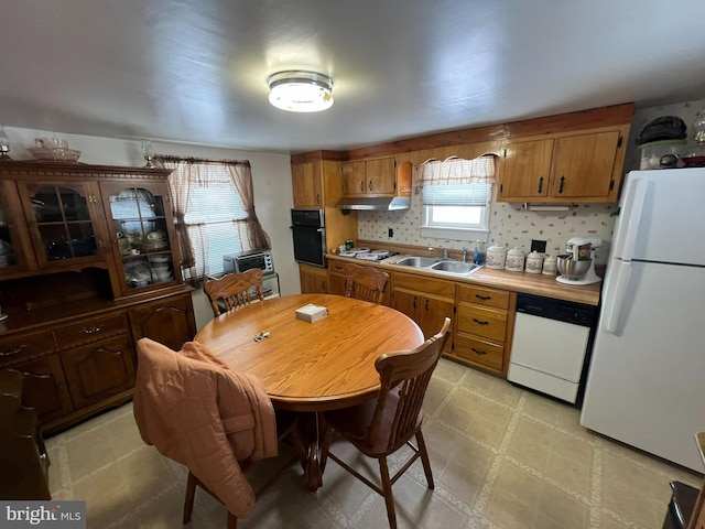 kitchen with backsplash, white appliances, sink, and a wealth of natural light