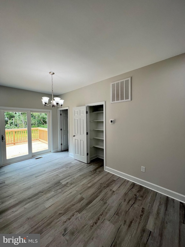 spare room featuring dark hardwood / wood-style floors and an inviting chandelier