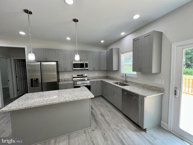 kitchen with gray cabinetry, a center island, hanging light fixtures, and appliances with stainless steel finishes