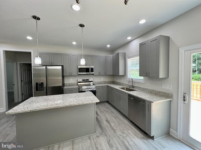 kitchen with appliances with stainless steel finishes, sink, a center island, gray cabinets, and hanging light fixtures