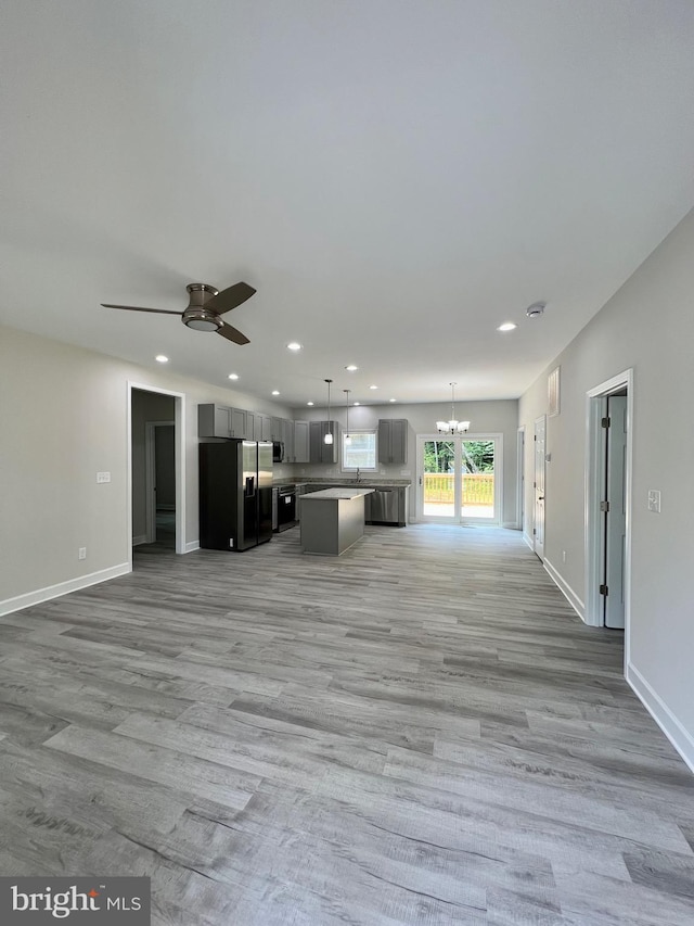 unfurnished living room with light hardwood / wood-style floors and ceiling fan with notable chandelier