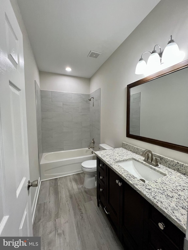 full bathroom with tiled shower / bath combo, toilet, wood-type flooring, and vanity