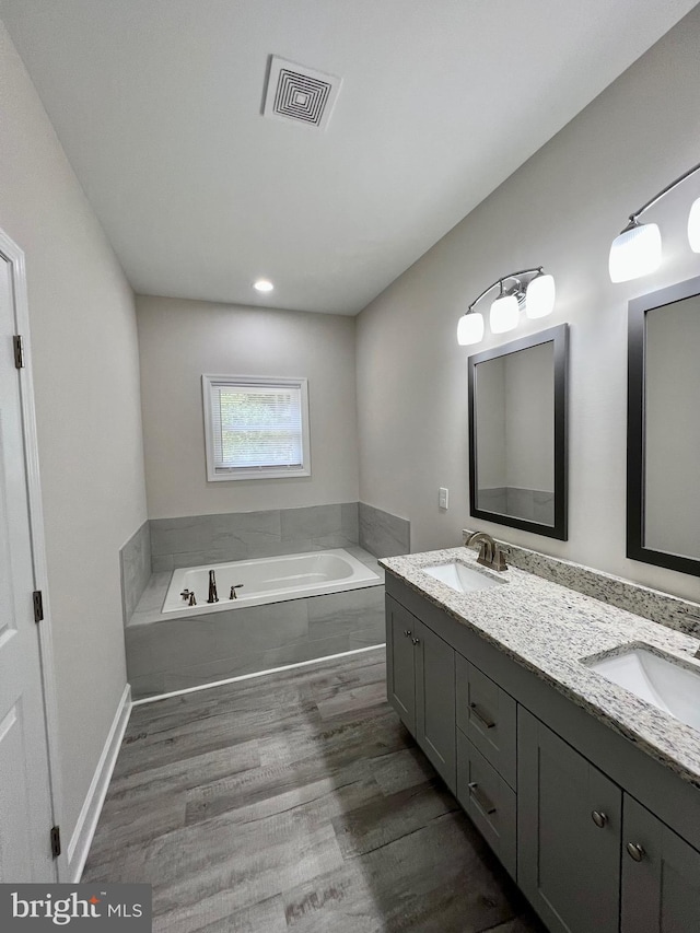 bathroom with vanity, wood-type flooring, and a tub