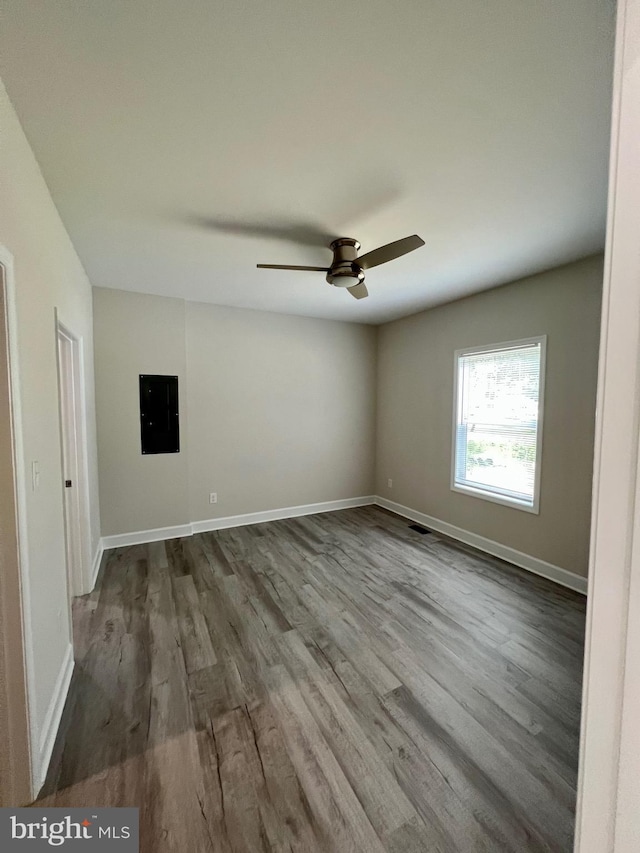 unfurnished room featuring hardwood / wood-style floors, electric panel, and ceiling fan