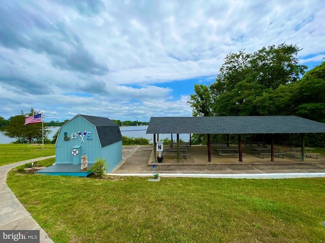 surrounding community with a water view, an outdoor structure, and a lawn