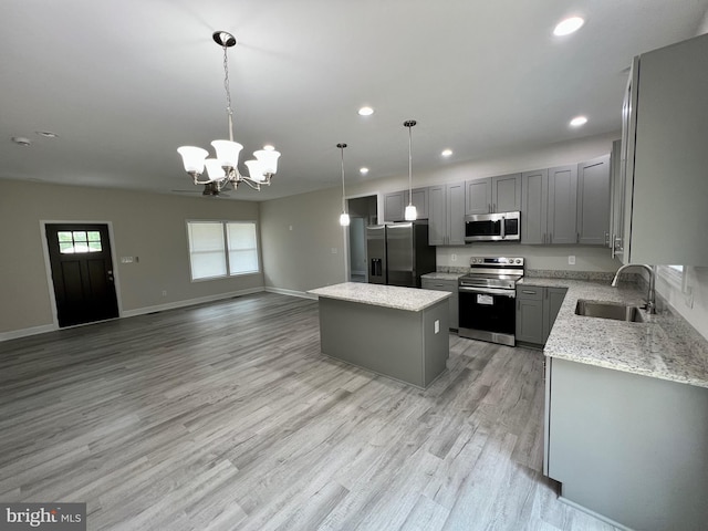 kitchen with gray cabinetry, hanging light fixtures, sink, appliances with stainless steel finishes, and a kitchen island