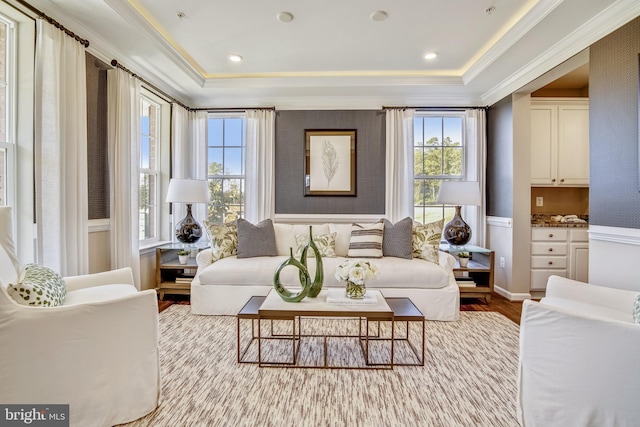 living area featuring a raised ceiling, crown molding, and light wood-type flooring