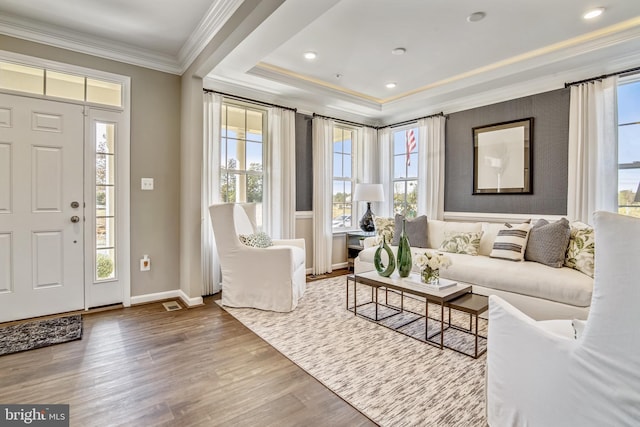 living room featuring hardwood / wood-style floors, a raised ceiling, and crown molding