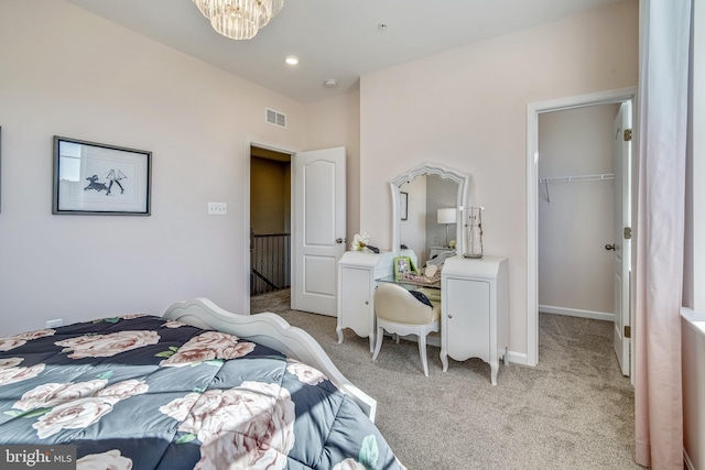 bedroom with a notable chandelier, light colored carpet, a spacious closet, and a closet