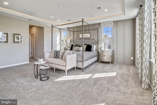 carpeted bedroom with a raised ceiling and multiple windows