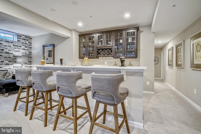 bar with light colored carpet and dark brown cabinetry