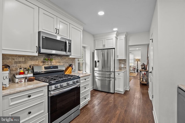 kitchen with dark wood-type flooring, white cabinets, decorative backsplash, light stone counters, and stainless steel appliances