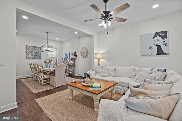 living room with dark wood-type flooring and ceiling fan with notable chandelier