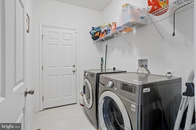 clothes washing area featuring light tile patterned floors and washing machine and dryer