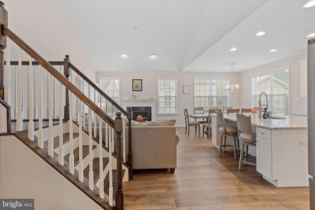 living room featuring vaulted ceiling, sink, a chandelier, and light hardwood / wood-style flooring