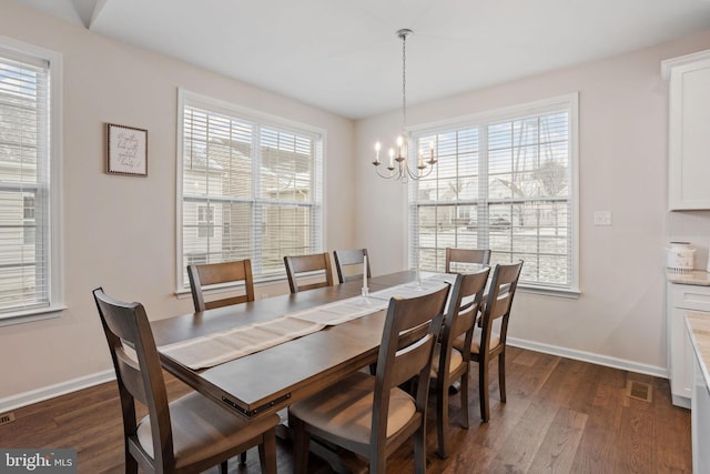 dining area featuring dark hardwood / wood-style flooring, a healthy amount of sunlight, and a notable chandelier