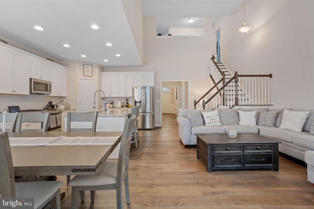 kitchen with appliances with stainless steel finishes, light hardwood / wood-style flooring, white cabinets, and decorative light fixtures