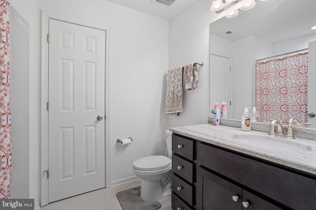 bathroom with toilet, vanity, and tile patterned floors