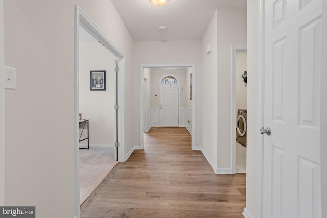 corridor with light wood-type flooring and washer / clothes dryer