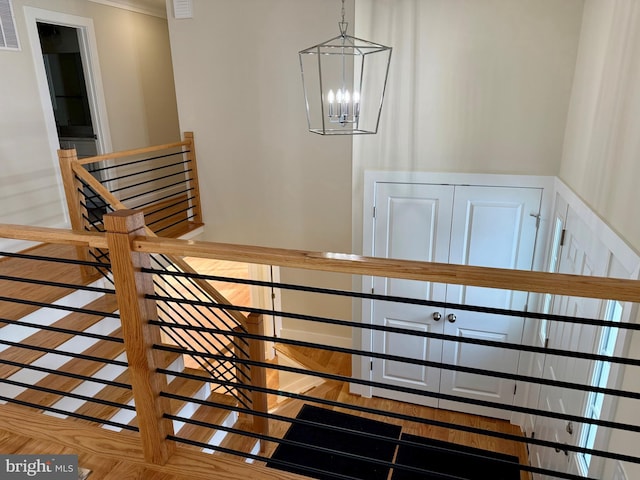 staircase with crown molding and a notable chandelier