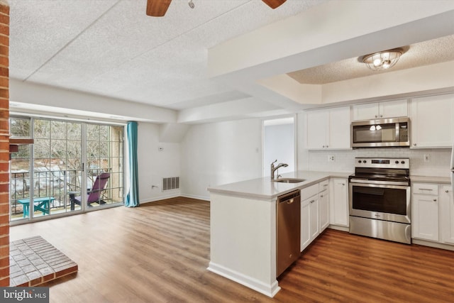 kitchen with white cabinets, sink, ceiling fan, kitchen peninsula, and stainless steel appliances