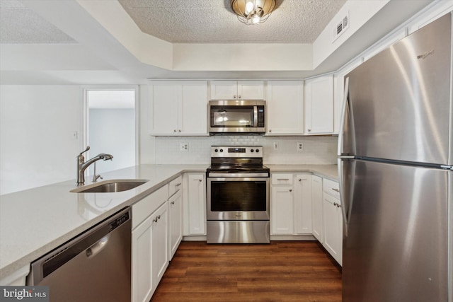 kitchen featuring appliances with stainless steel finishes, tasteful backsplash, sink, white cabinets, and dark hardwood / wood-style floors