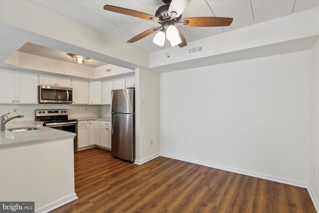 kitchen with decorative backsplash, stainless steel appliances, ceiling fan, sink, and white cabinetry