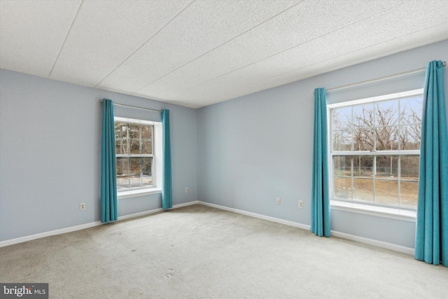 spare room featuring light carpet and a wealth of natural light