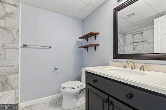 bathroom featuring a drop ceiling, toilet, and vanity