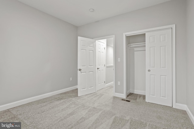 unfurnished bedroom featuring light carpet and a closet