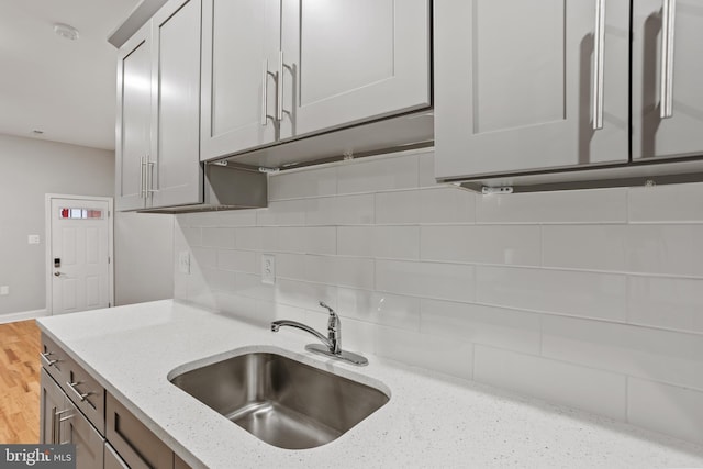 kitchen with light stone countertops, tasteful backsplash, and sink