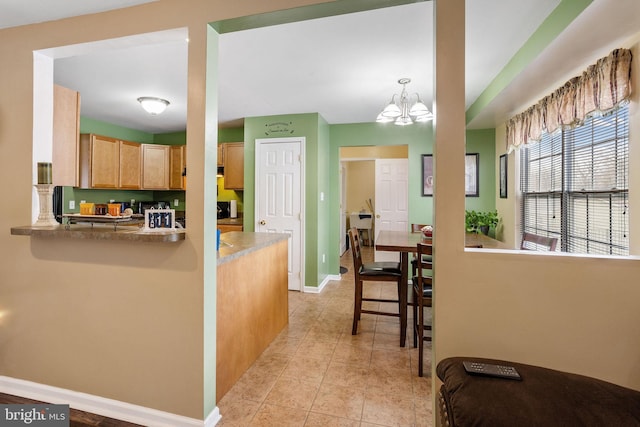 kitchen with kitchen peninsula, light tile patterned floors, hanging light fixtures, and an inviting chandelier