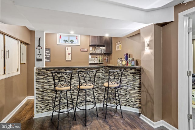 bar featuring dark hardwood / wood-style flooring and dark brown cabinets