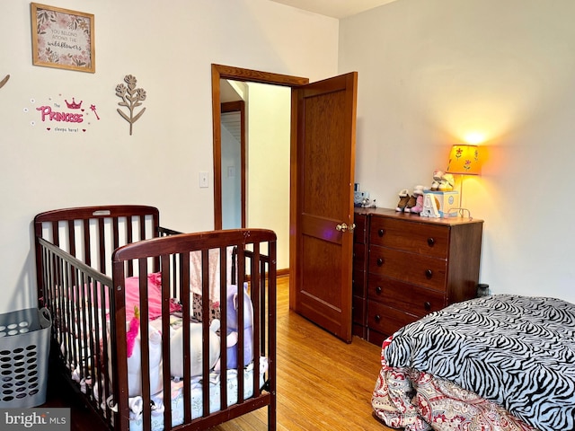 bedroom featuring light hardwood / wood-style floors and a nursery area