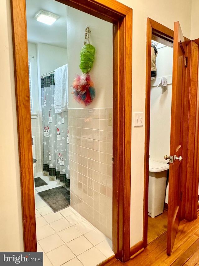 bathroom with a shower with shower curtain, tile patterned flooring, and tile walls