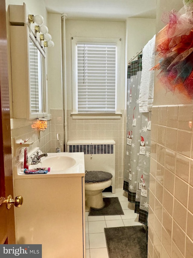 bathroom with tile walls, tile patterned floors, vanity, and radiator heating unit