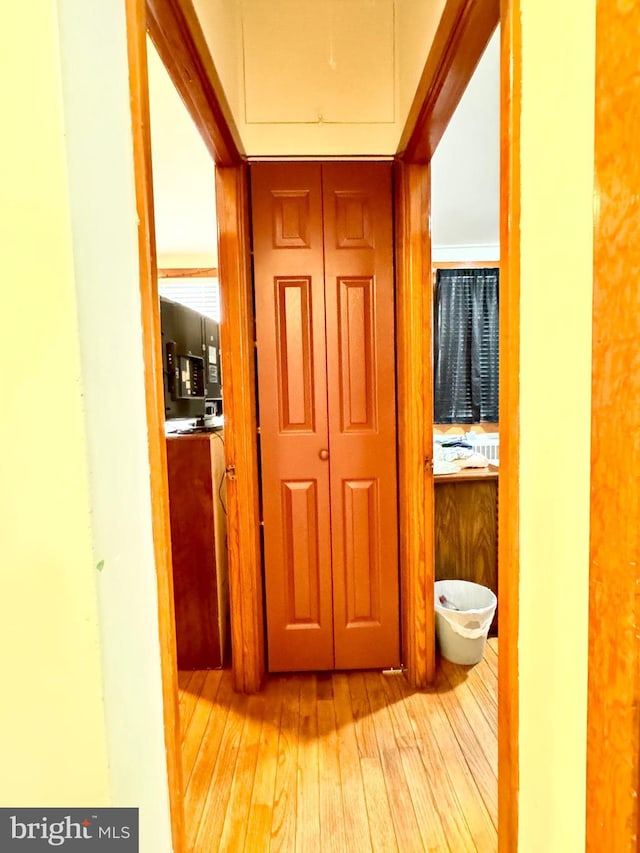 corridor with light hardwood / wood-style flooring and crown molding