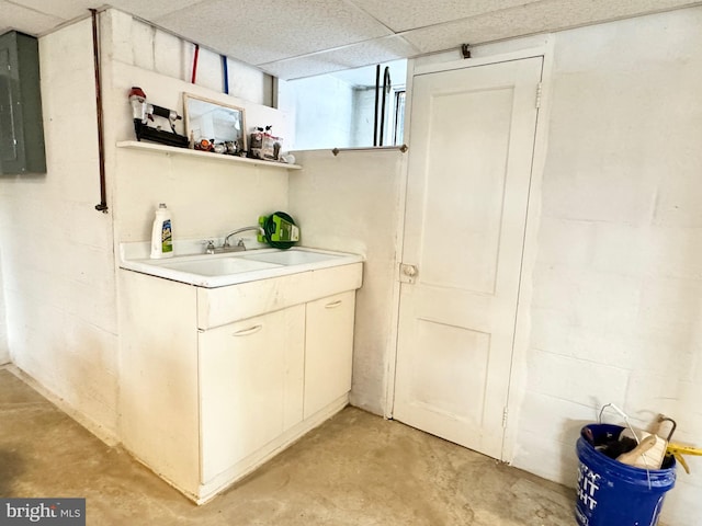 interior space with a paneled ceiling, sink, and electric panel