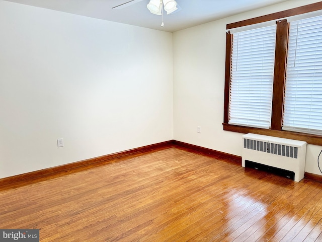 unfurnished room featuring ceiling fan, wood-type flooring, and radiator heating unit