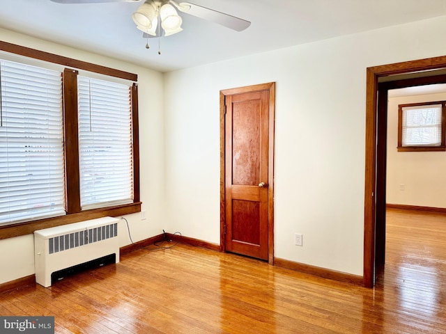 spare room featuring radiator, ceiling fan, and light hardwood / wood-style floors