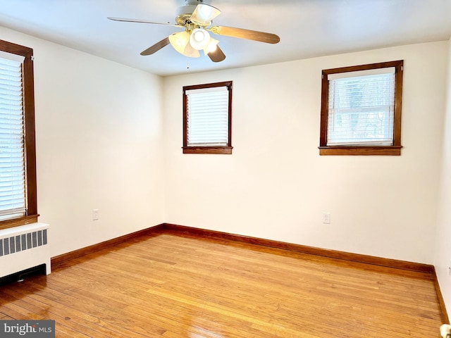 empty room with ceiling fan, radiator, and light hardwood / wood-style flooring