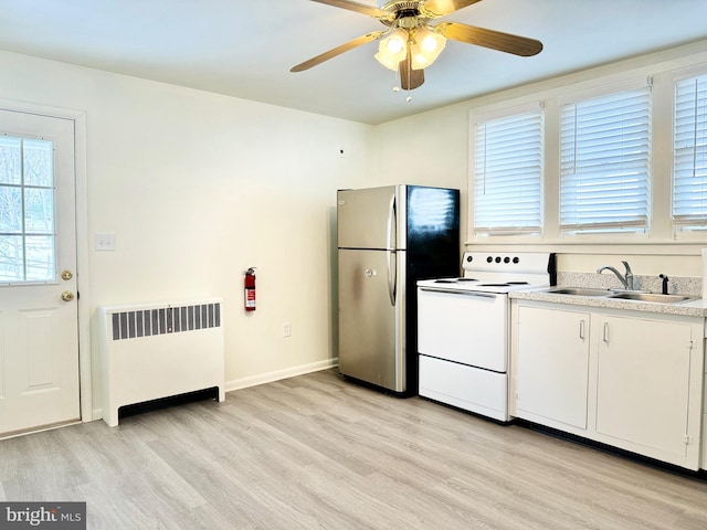 kitchen with radiator heating unit, white electric range oven, stainless steel refrigerator, white cabinets, and sink