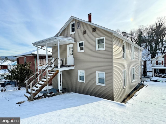 snow covered property with covered porch