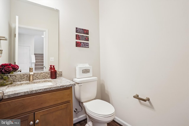 bathroom featuring baseboards, vanity, and toilet