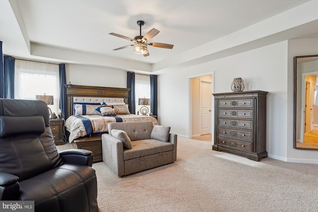 carpeted bedroom featuring a tray ceiling, ceiling fan, and baseboards