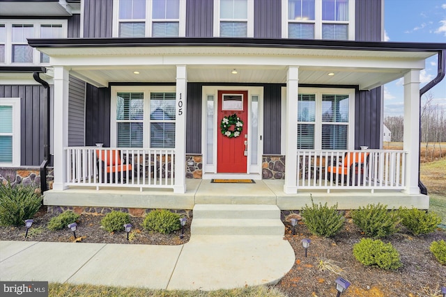 exterior space with board and batten siding, covered porch, and stone siding