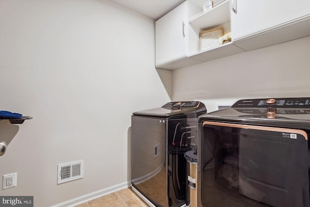 washroom with cabinet space, visible vents, baseboards, washing machine and clothes dryer, and light tile patterned flooring